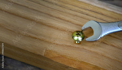 Close-up wrench screwing nut a furniture screw into a wooden plank, The effort  wrong of tools as a fail concept photo