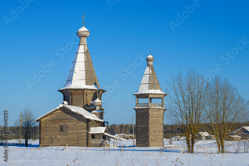 View of the old church of St. John Chrysostom with a bell tower (1665) on a sunny February day. Saunino, Kargopol district. Arkhangelsk region, Russia photo