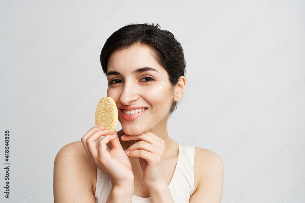 Pretty brunette clean face skin Sponge in hands with cosmetics Pretty brunette clean face skin Sponge in hands with cosmetics