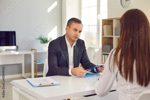 Foto Serious male HR manager interviewing female job candidate asking her questions concerning the experience she stated on her resume