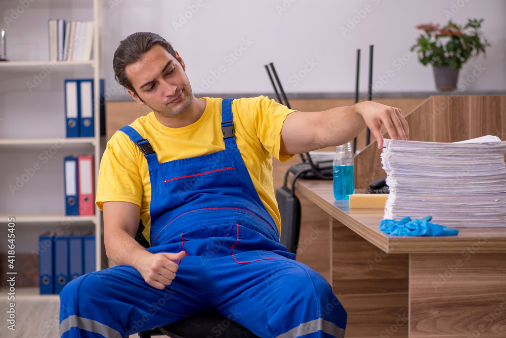 Obraz premium Young male contractor cleaning the office in industrial espionag