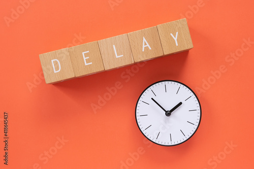 遅れ、遅延｜「DELAY」と書かれた積み木と時計 photo