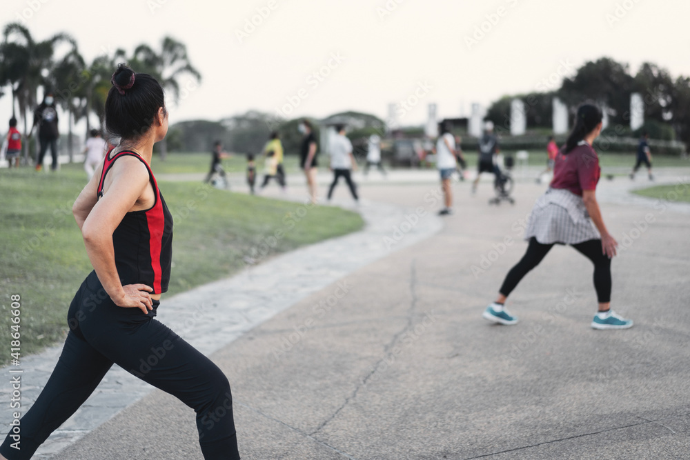 Rearview of matured healthy people doing aerobics dance in the city park in the evening after work to relax and get a healthy life. Sports and recreation Rearview of matured healthy people doing aerobics dance in the city park in the evening after work to relax and get a healthy life. Sports and recreation