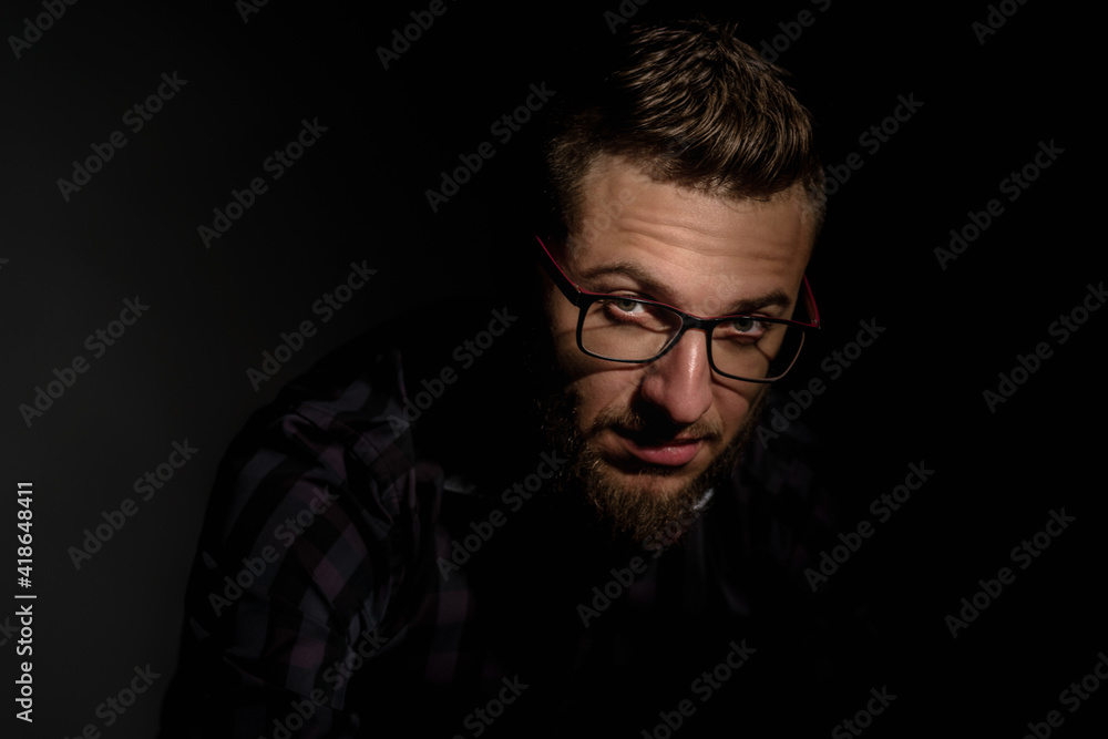Studio portrait of young bearded man in glasses on dark background Studio portrait of young bearded man in glasses on dark background