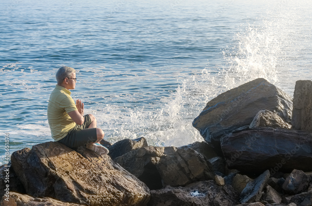Man meditating on rock in beach coast