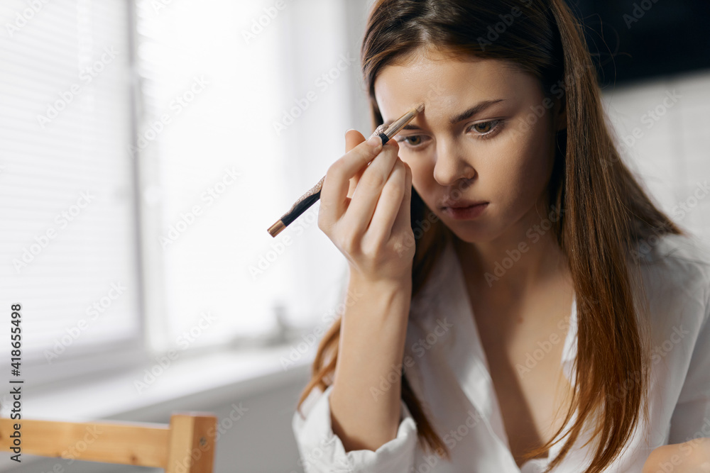 red-haired woman in a shirt with an eyeliner in her hand a foundation eyeliner red-haired woman in a shirt with an eyeliner in her hand a foundation eyeliner