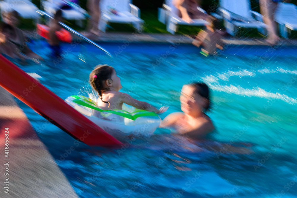 Children's slide in the pool, the visible movement of the descent down the hill, entertainment in the outdoor water park.
