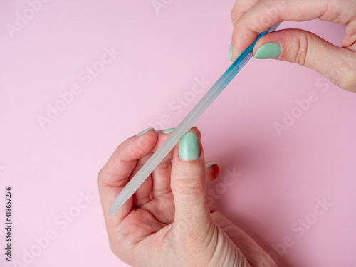 Foto a woman herself is filing her nails with a nail file on her hand on a pink background
