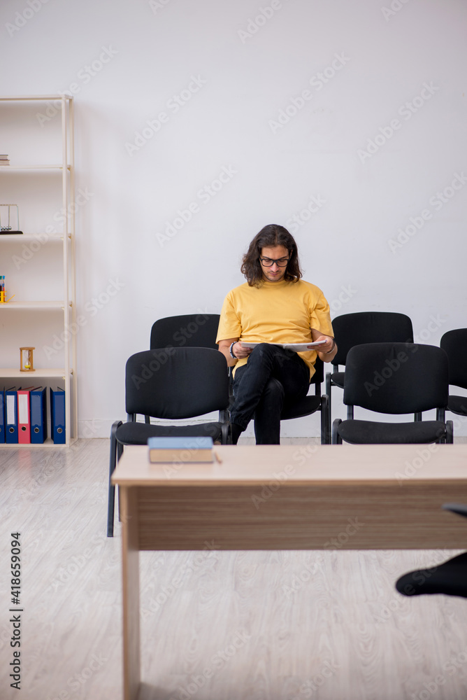 Fototapeta premium Young male student waiting for teacher in the classroom