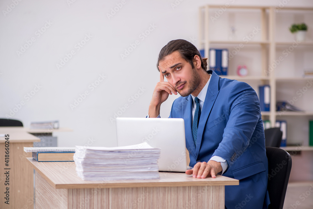 Young male employee and too much work in the office Young male employee and too much work in the office
