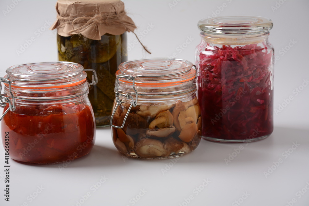 Jars of Homemade pickled vegetables: cucumbers, tomatoes, honey agarics mushrooms, on white background. Marinated and Fermented food. Fermented preserved vegetarian food concept. Jars of Homemade pickled vegetables: cucumbers, tomatoes, honey agarics mushrooms, on white background. Marinated and Fermented food. Fermented preserved vegetarian food concept.