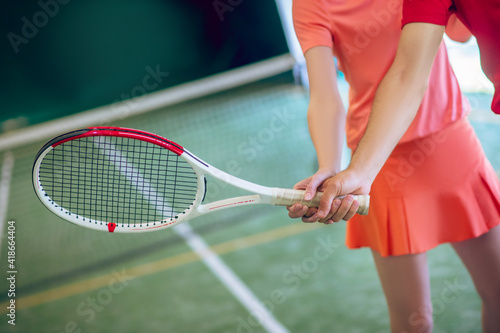 Tennis coach in red cap training a dark-haired woman