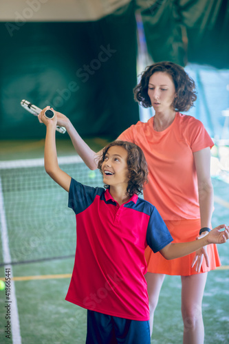 Dark-haired boy having a tennis workout with his coach