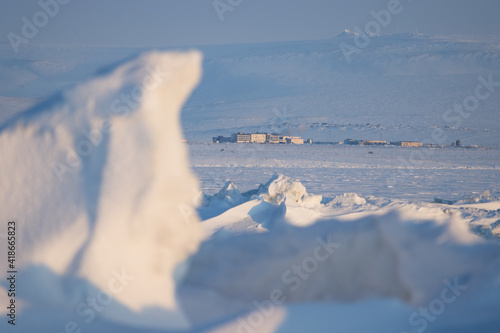 Winter Arctic landscape. In the distance, the building of the airport Anadyr (Ugolny). In the foreground are large ice hummocks on the frozen surface of the Anadyr estuary. Chukotka, Siberia, Russia. © Andrei Stepanov