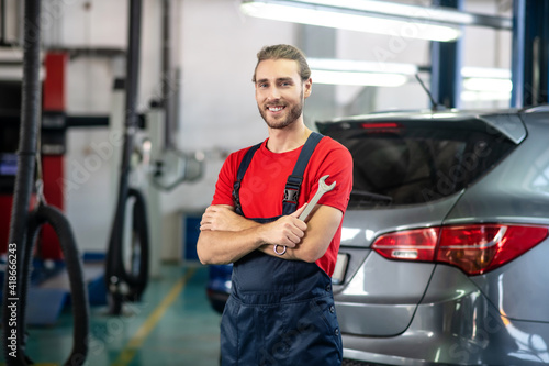 Smiling man with wrench in auto repair shop