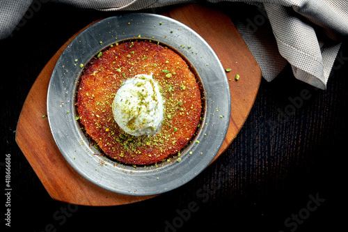 Appetizing Turkish sweetness Kanafeh made with shredded filo pastry with honey, pistachios and white ice cream photo