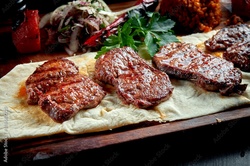 Grilled beef fillet with bulgur and vegetables garnished on a wooden board. Turkish kebab. Close up, selective focus Grilled beef fillet with bulgur and vegetables garnished on a wooden board. Turkish kebab. Close up, selective focus