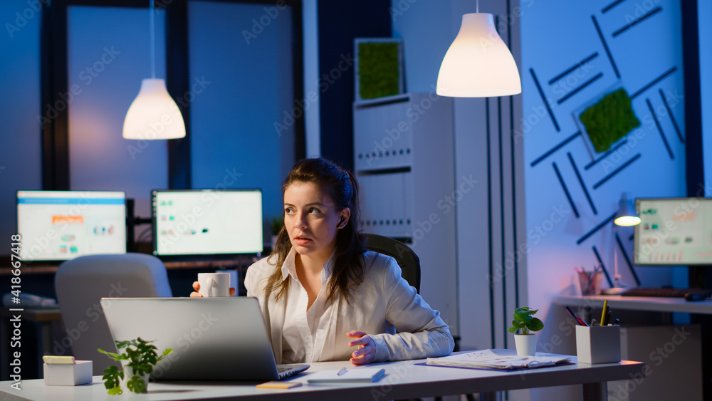 Manager speaking online with remotely coworkers late at night sitting in busineess office at laptop in midnight. Employee using technology network wireless talking on virtual meeting doing overtime Manager speaking online with remotely coworkers late at night sitting in busineess office at laptop in midnight. Employee using technology network wireless talking on virtual meeting doing overtime