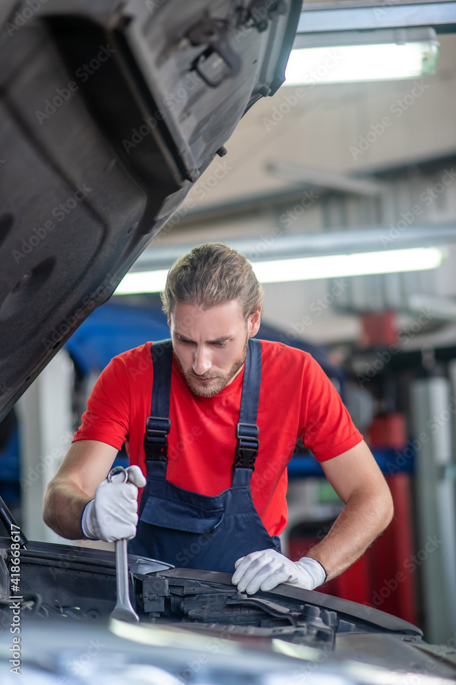 Experienced repairer doing repairs in car hood Experienced repairer doing repairs in car hood