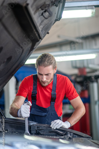 Experienced repairer doing repairs in car hood