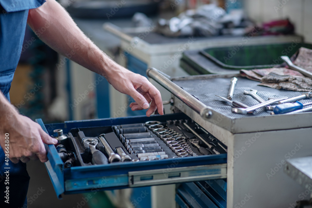 Male hands opening box with working tool Male hands opening box with working tool