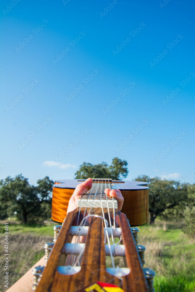 Creative Photography Of A Hand Holding A Spanish Guitar With Nature Background. Spanish Classical Guitar Exterior. Music And Nature Creative Photography Of A Hand Holding A Spanish Guitar With Nature Background. Spanish Classical Guitar Exterior. Music And Nature