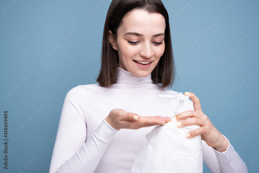 Young girl sanitizer in hands in the studio on a blue background. Hand disinfection and germ prevention. Young girl sanitizer in hands in the studio on a blue background. Hand disinfection and germ prevention.