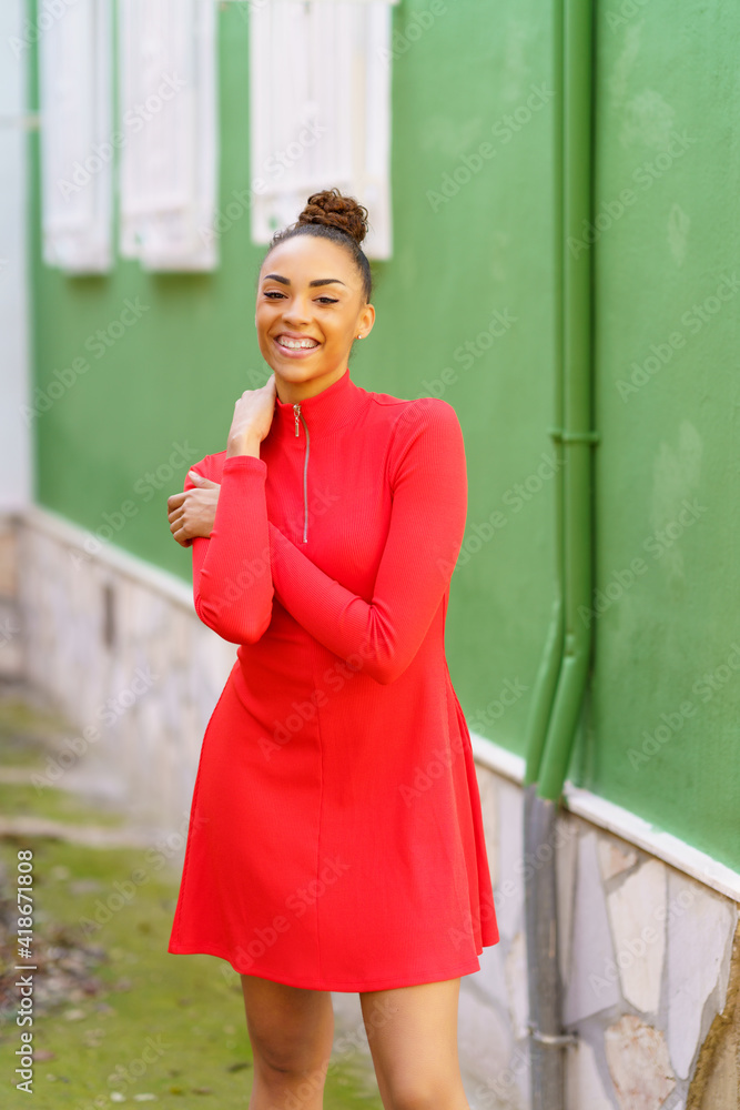 Happy black woman in red dress in front of a green wall
