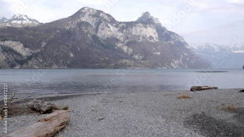 Dolly tilt up on a beach to reveal beautiful lake and Swiss alps.