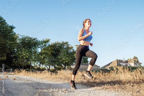 Young woman in sportswear running in the park © javidestock