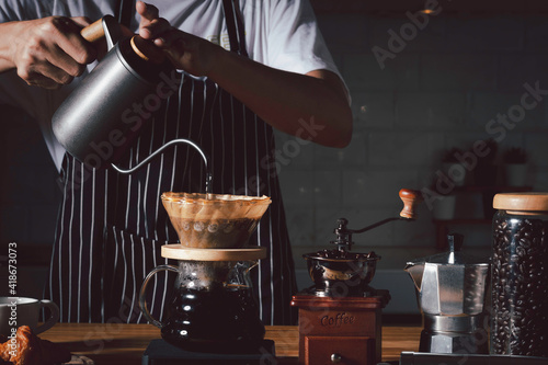 Coffee shop concept : Professional barista preparing coffee using chemex pour over coffee maker and drip kettle. Alternative ways of brewing coffee.