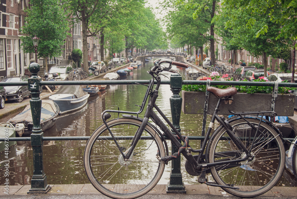 Amsterdam, Holland, May 12 2018: Old bicycle parked on a canal bridge in Amsterdam