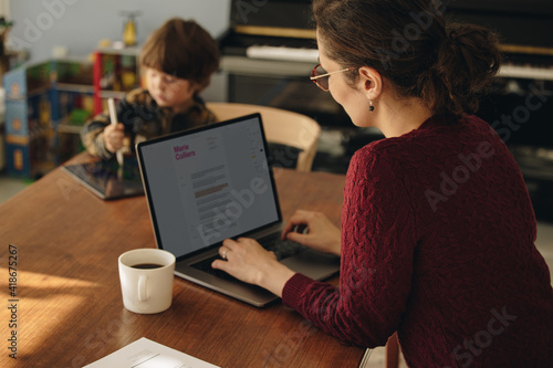 Woman working from home with son using tablet