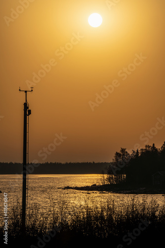 Sunrise in a boreal forest sea bay with weather station