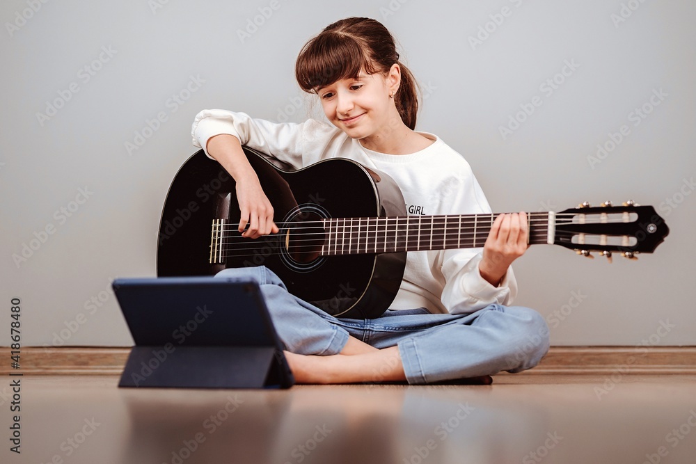Niña tomando clases de guitarra online por la tablet Stock Photo | Adobe  Stock