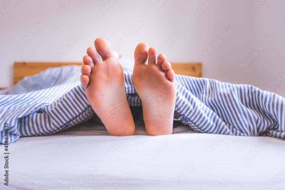 Enjoying the morning in bed Close up of uncovered female feet in the
