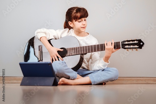 Niña tomando clases de guitarra online por la tablet