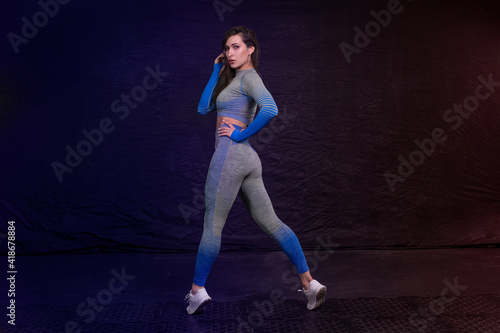 girl in fitness clothes posing stood up on socks. dark background