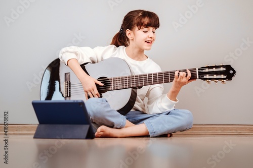 Niña tomando clases de guitarra online por la tablet