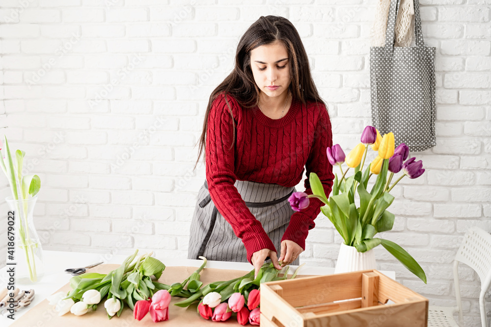 Woman florist making a bouquet of fresh colorful tulips