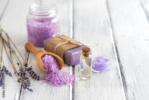 Lavender spa products on an old white wooden table. Body care products with lavender; oil, salt, cream, soap and dried lavender flowers. Selective focus.