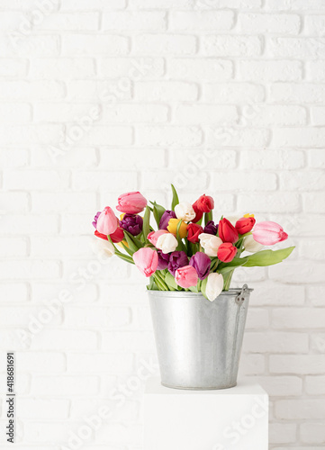 Bucket of tulip flowers over white brick wall background