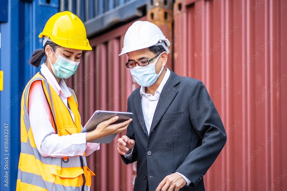Industrial worker woman and engineer control worker using tablet device and meeting in front of container and cargo. Business people with confident and smart working in shipping transport industry Industrial worker woman and engineer control worker using tablet device and meeting in front of container and cargo. Business people with confident and smart working in shipping transport industry
