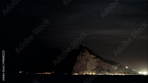 Time lapse of clouds moving over Gibraltar rock atnight. View from Torrecarbonera beach, Punta Mala, Andalusia Spain. Tourist attraction. photo