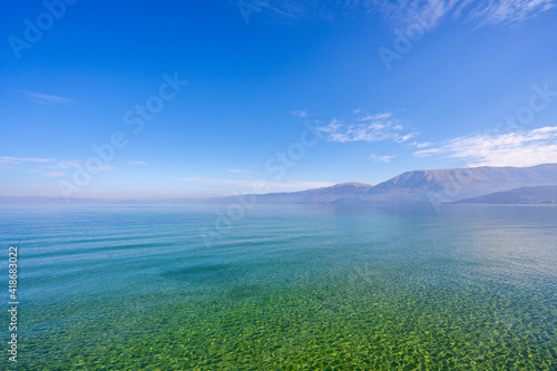 Amazing view on the green tree  mountains  sea with turquoise water and colorful blue sky at sunrise. Summer landscape in mountains on seashore.