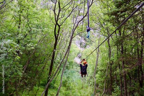 Fotografie von einem Mann, der mit einer Zipline durch durch einen Wald gleitet.