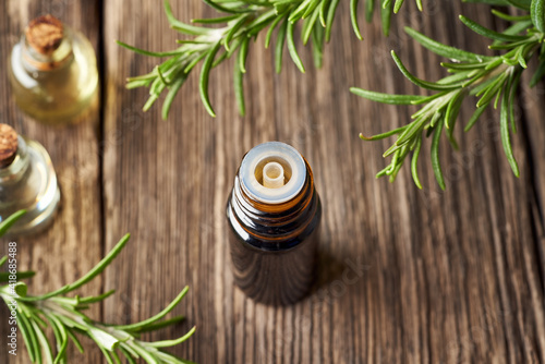 A bottle of rosemary essential oil with fresh rosemary