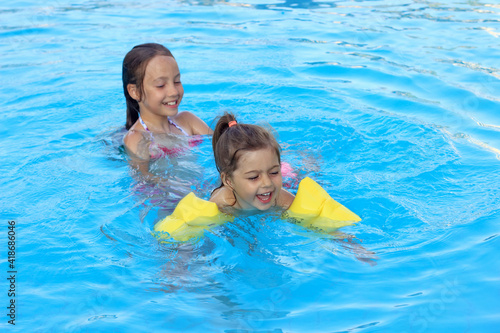 Happy beautiful  little girls swimming in outdoor pool at sunset.