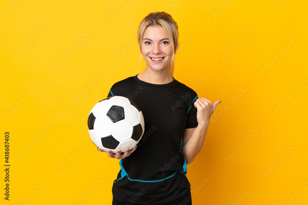 Young Russian football player woman isolated on yellow background pointing to the side to present a product Young Russian football player woman isolated on yellow background pointing to the side to present a product