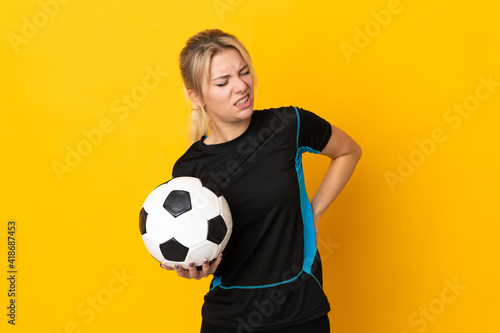 Young Russian football player woman isolated on yellow background suffering from backache for having made an effort © luismolinero